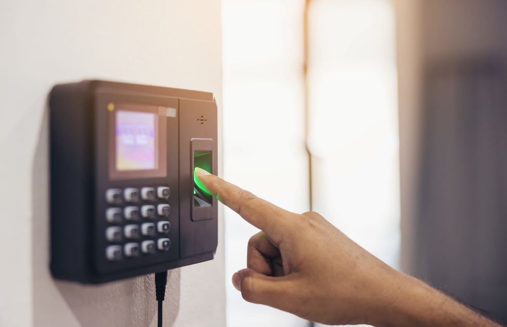 Funcionário registra biometria em aparelho eletrônico, ilustrando o uso de controle de ponto digital em ambiente corporativo.