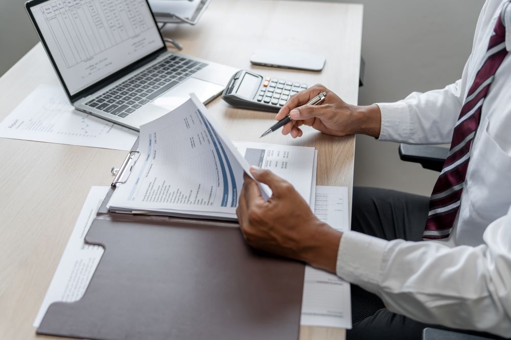 Profissional analisa documentos, planilhas e relatórios em uma mesa de trabalho durante a implantação de BPO de folha de pagamento.