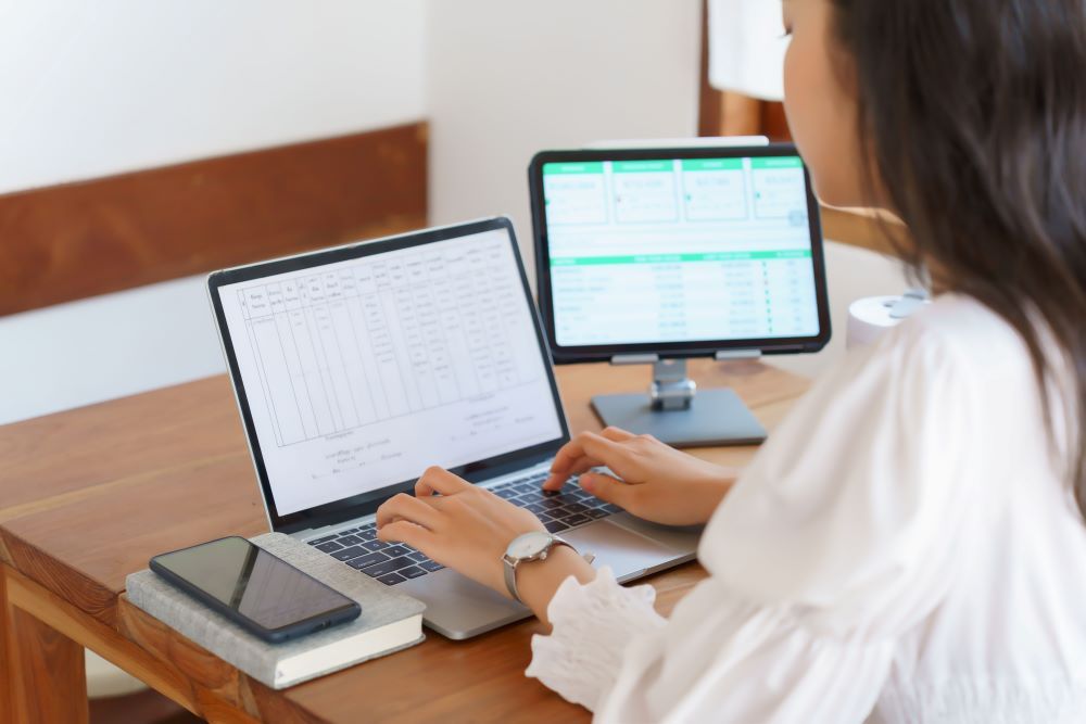 Profissional utiliza software de folha de pagamento em notebook e monitor para gerenciar cálculos salariais, dados de colaboradores e processos do departamento pessoal de forma automatizada e segura.