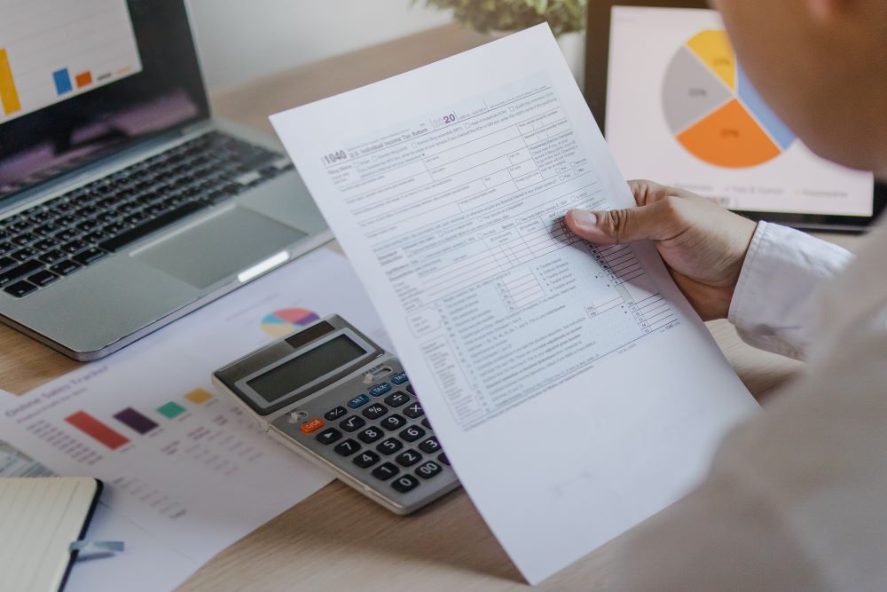 Pessoa analisa documento financeiro com calculadora relacionada ao décimo terceiro salário.