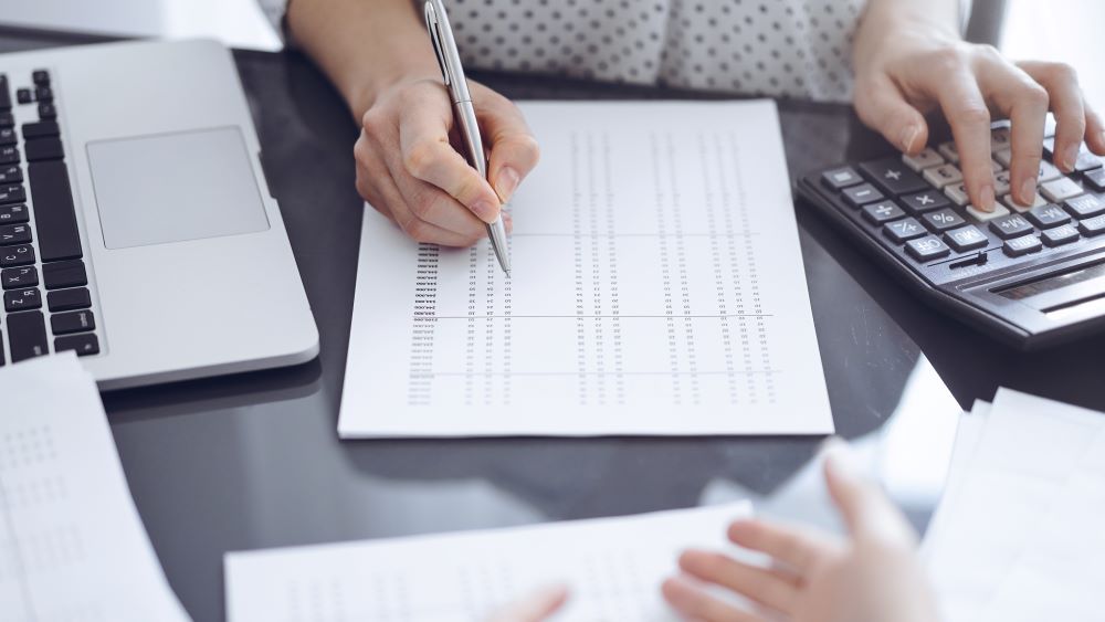 Pessoa analisa cálculos financeiros com calculadora relacionados ao abono pecuniário.