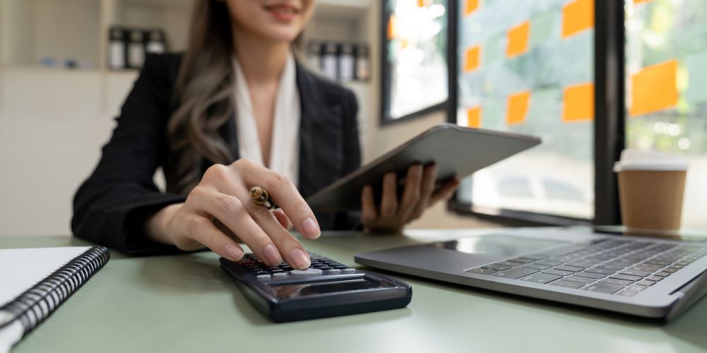 Profissional de RH realizando cálculo de aviso prévio indenizado com calculadora e tablet em ambiente corporativo, analisando verbas rescisórias e rescisão contratual.