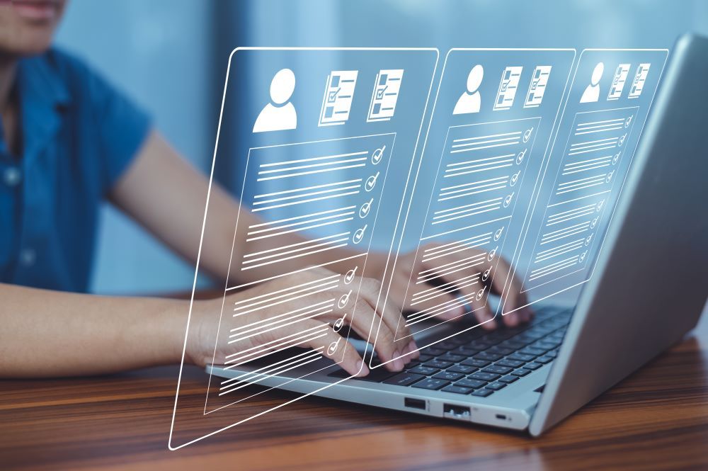 Profissional de RH utilizando laptop para comparar BPO vs software de folha de pagamento, com interfaces digitais de gestão de colaboradores projetadas na tela.