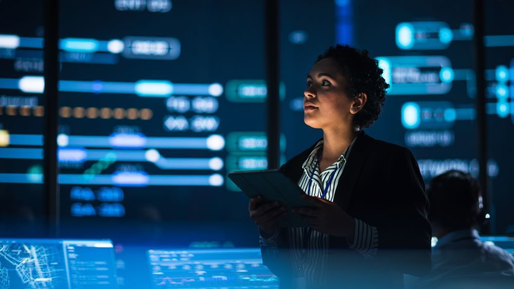 Profissional analisa dados em uma central tecnológica com telas digitais ao fundo, representando a atuação do DPO na proteção e governança de dados.