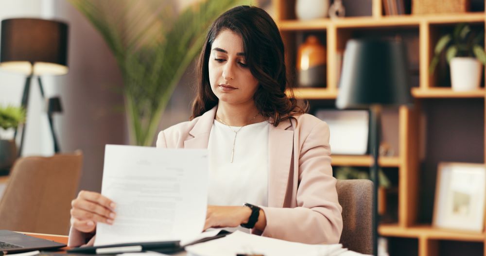 Analista de departamento pessoal revisando documentos admissionais em mesa de trabalho, representando o processo de admissão CLT e conformidade trabalhista.