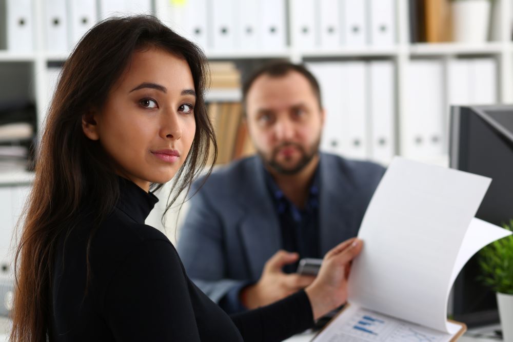 Profissionais analisam documentos em um escritório, representando a verificação de procedimentos de compliance trabalhista.