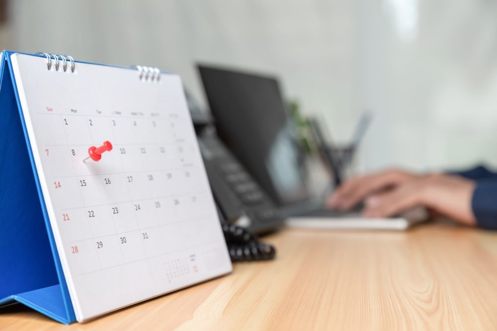 Calendário de mesa com data marcada em vermelho representa consulta e organização do calendário PIS em ambiente de escritório.