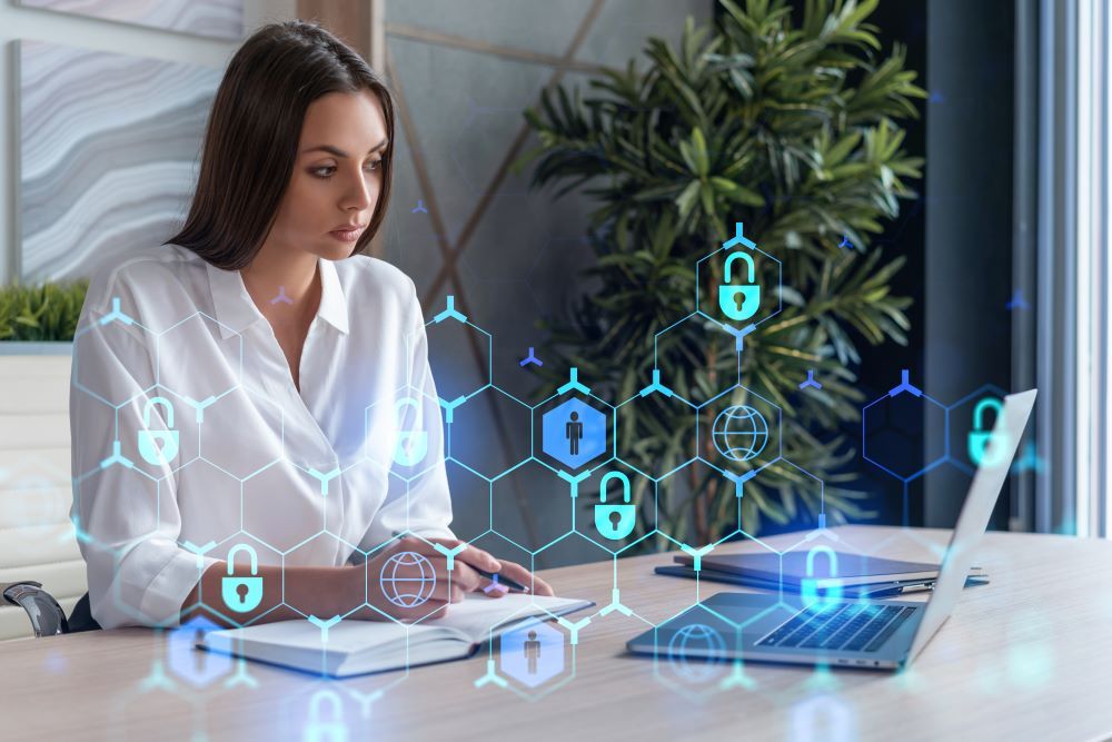 Profissional trabalha em escritório com símbolos digitais de proteção de dados, representando a segurança e a aplicação da LGPD no RH.